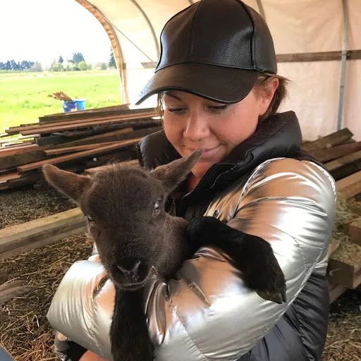 A woman is holding a baby goat in her arms